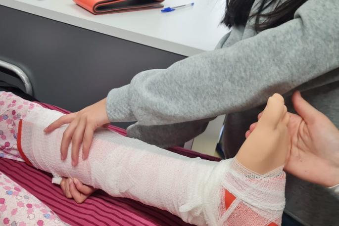 © Hanna Fisher Bild zeigt wie eine Schülerin einer speziellen Puppe für die Pfegeausbildung einen Verband anlegt